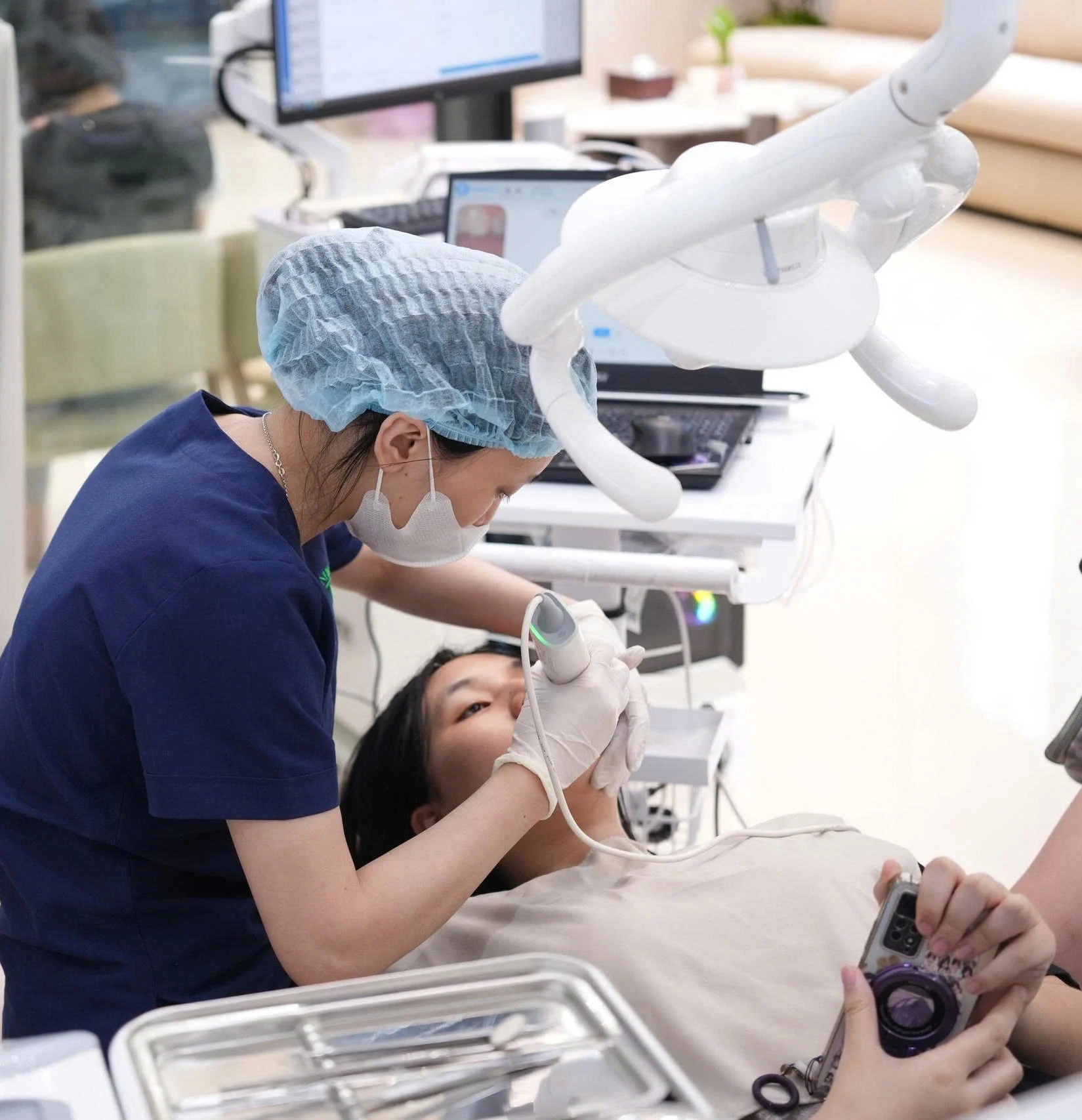Nhân viên y tế dùng máy quét trong miệng cho người bệnh tại phòng khám